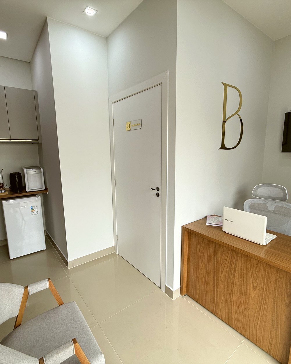 Recepção da Buzzo Odontologia, com o monograma B dourado na parede